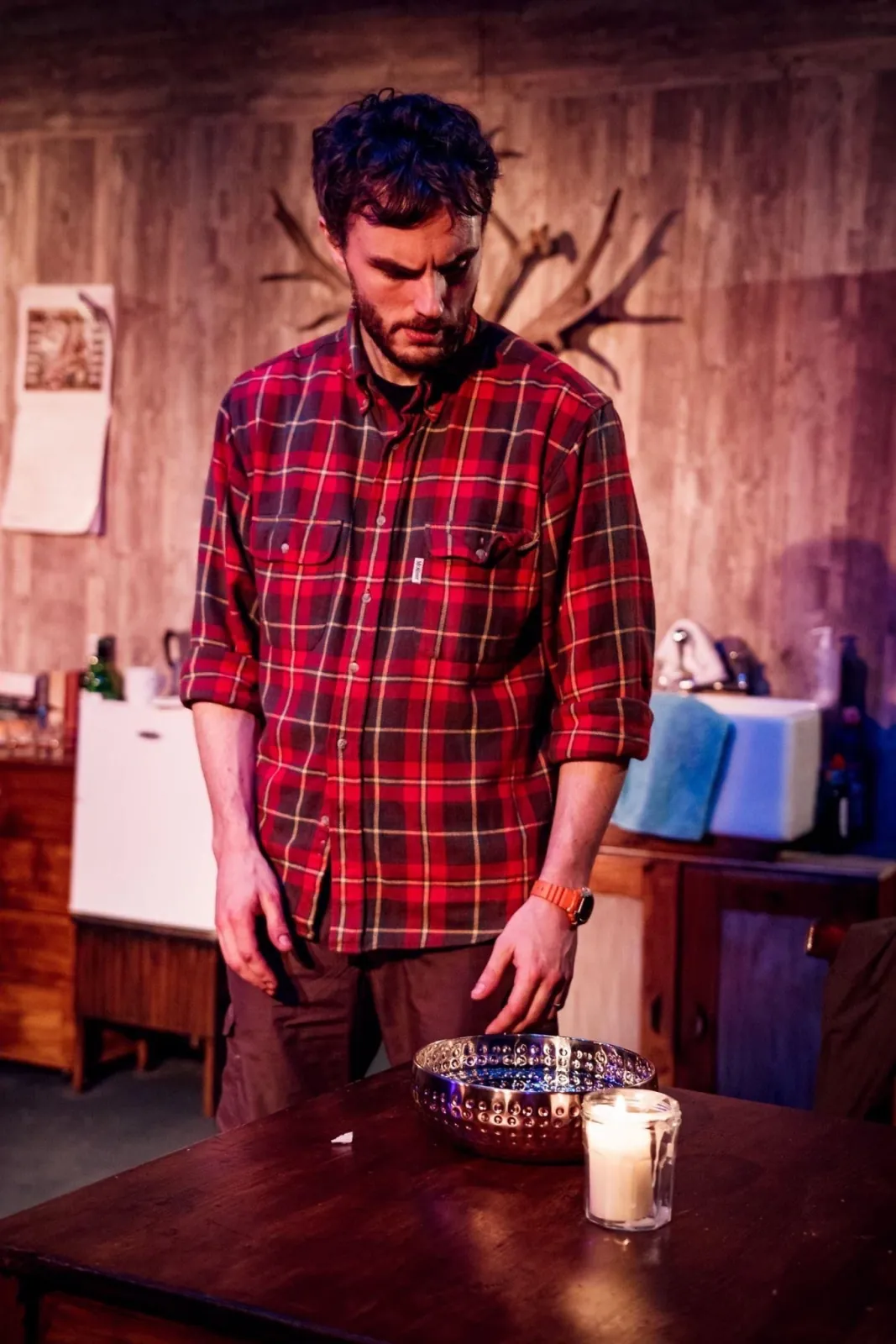Danny Solomon on stage — plaid shirt, candlelit ritual scene