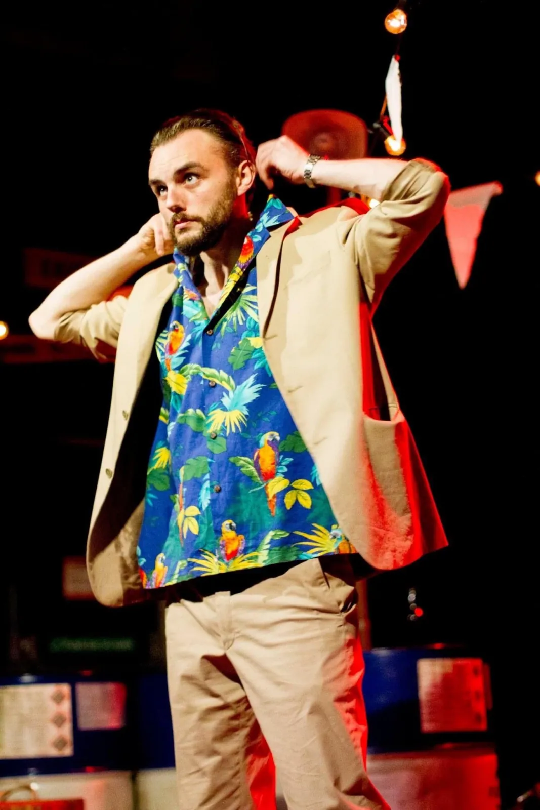 Danny Solomon on stage — tropical shirt, string lights, arm raised