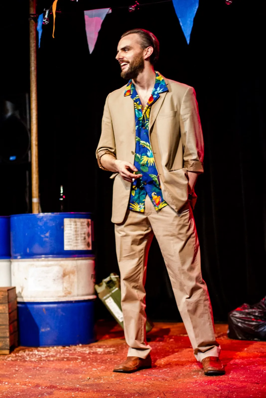Danny Solomon on stage — tropical shirt, smiling, blue barrels