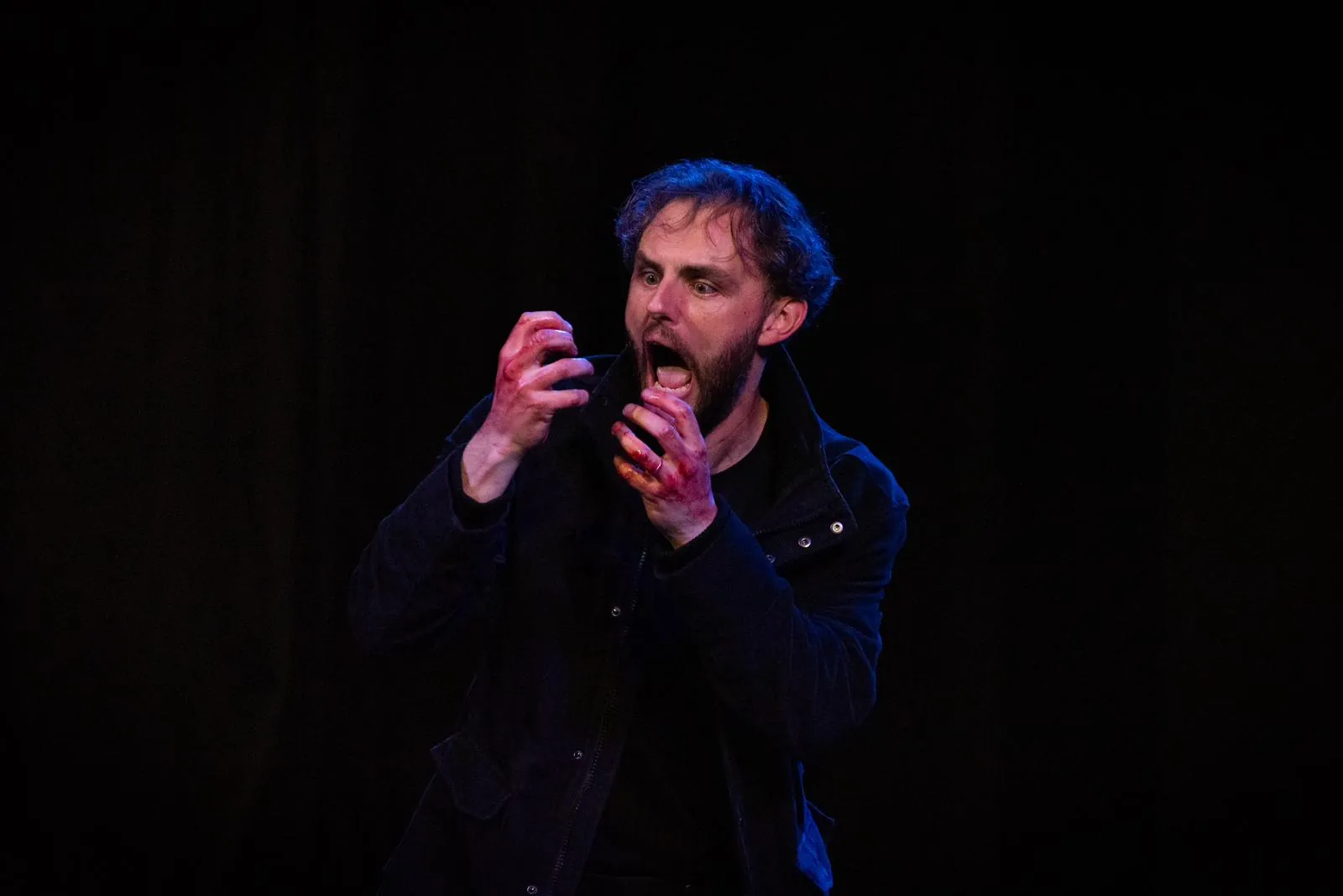 Danny Solomon on stage — screaming, blood on hands, dark jacket