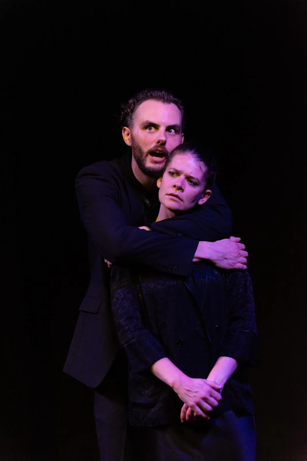 Danny Solomon on stage — embracing a co-star from behind