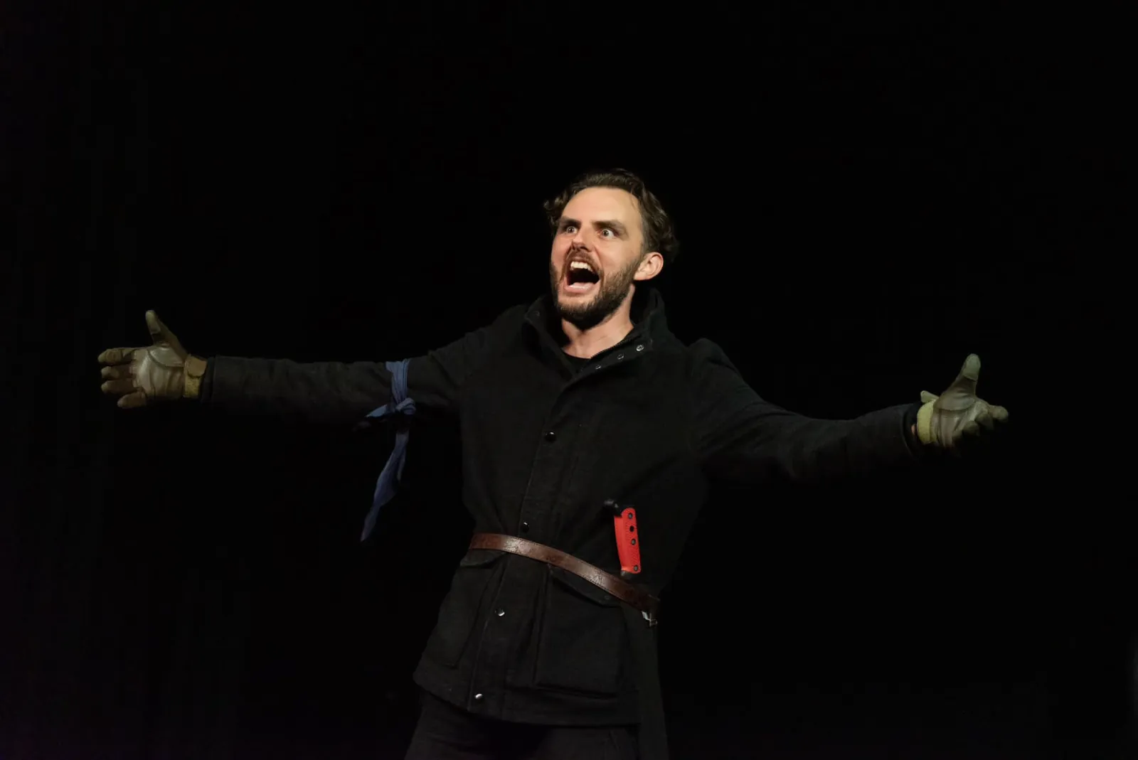 Danny Solomon on stage — arms outstretched, dark coat