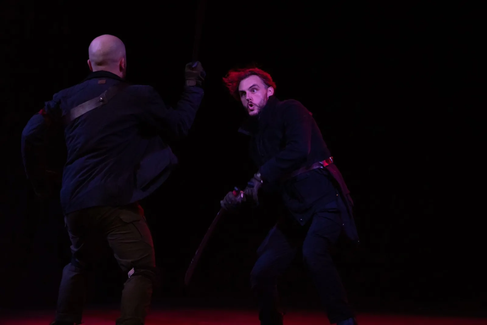 Danny Solomon on stage — stick fight, red lighting
