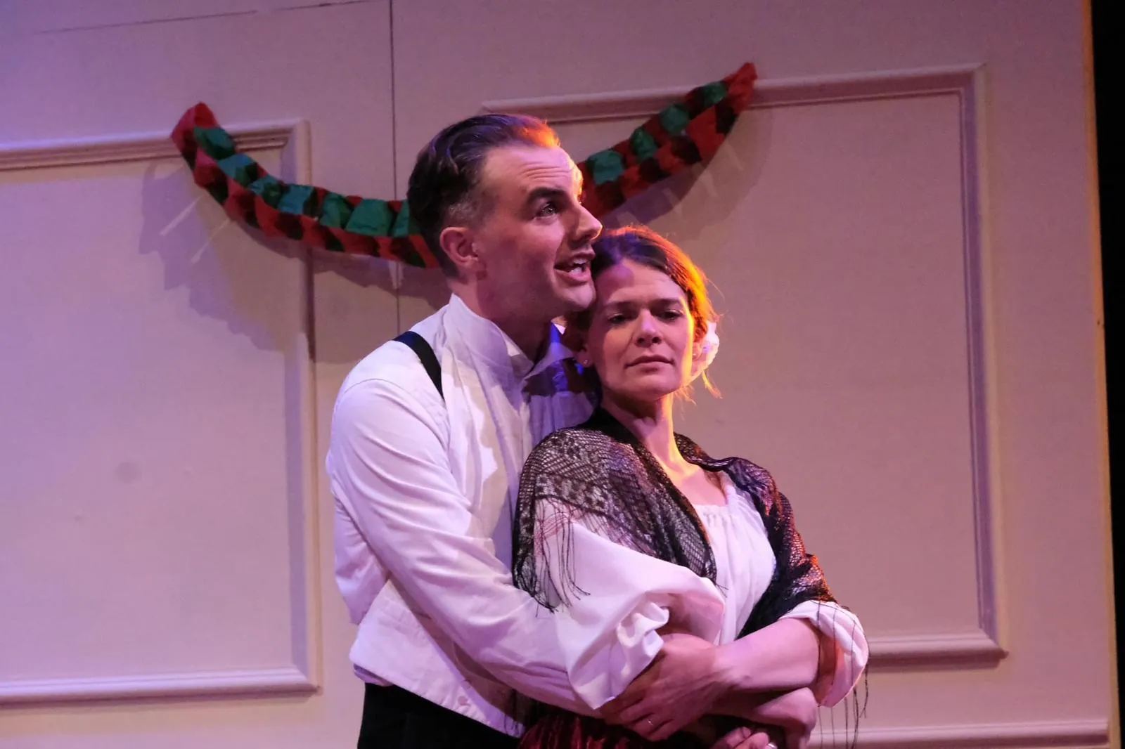 Danny Solomon on stage — period costume embrace, paper garland