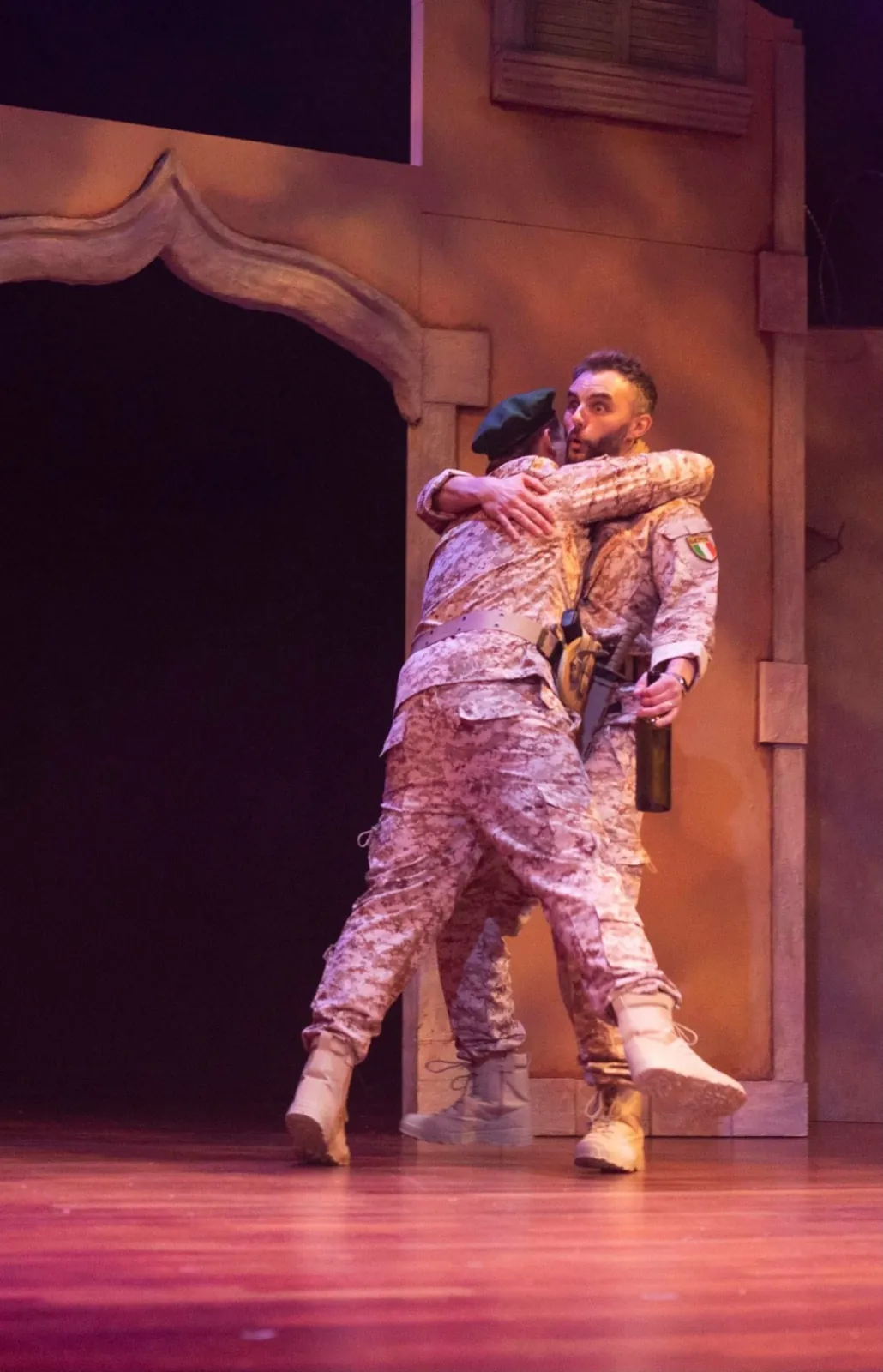 Danny Solomon on stage — embracing a co-star in desert uniform