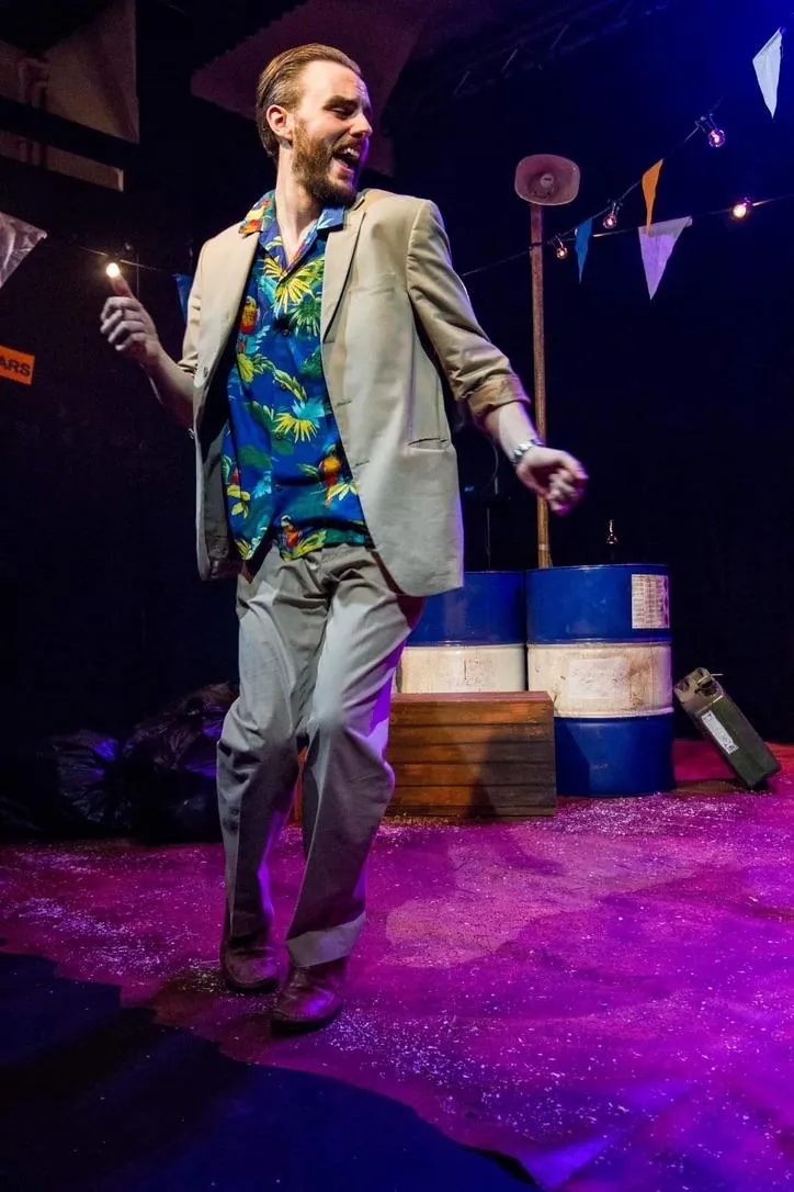 Danny Solomon on stage — tropical shirt, dancing, pink light