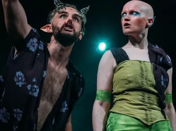 Danny Solomon on stage — devil horns, with co-star in green