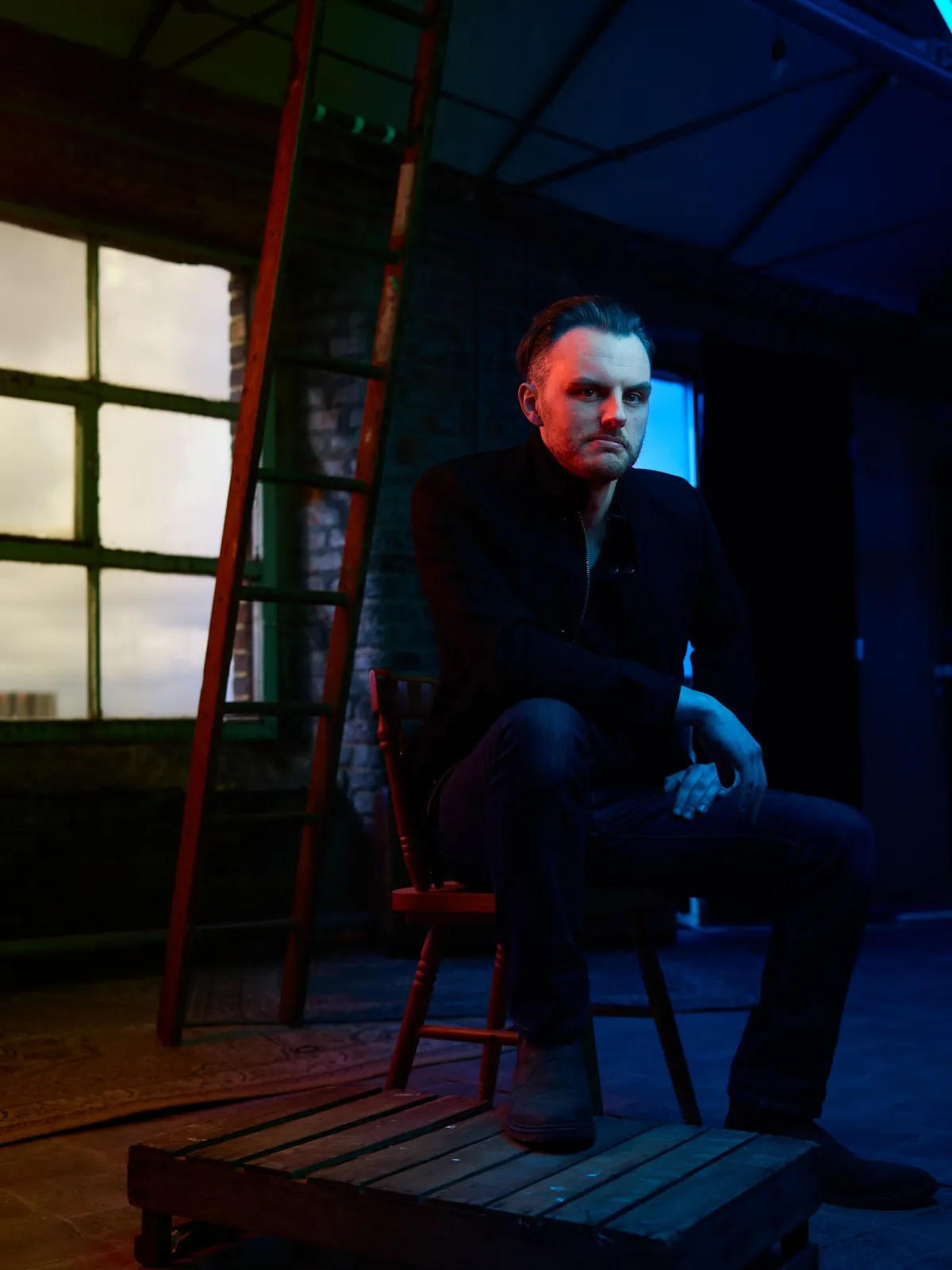 Danny Solomon on stage — seated, moody blue and red lighting
