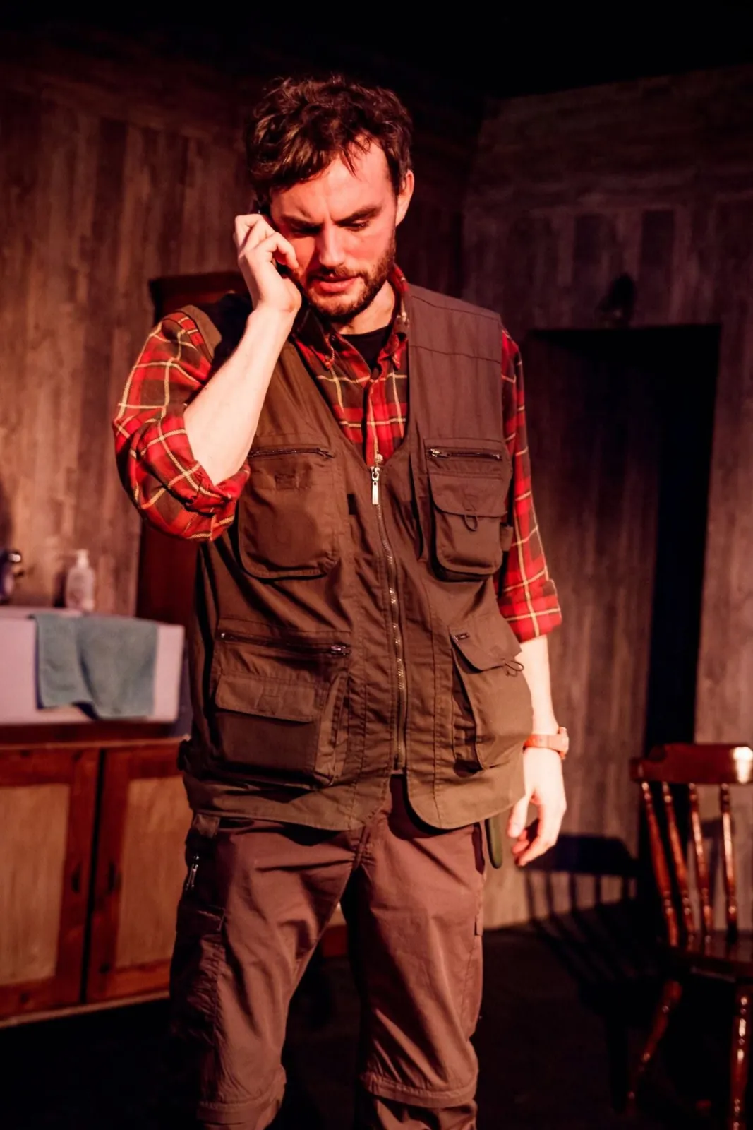 Danny Solomon on stage — plaid utility vest, on the phone