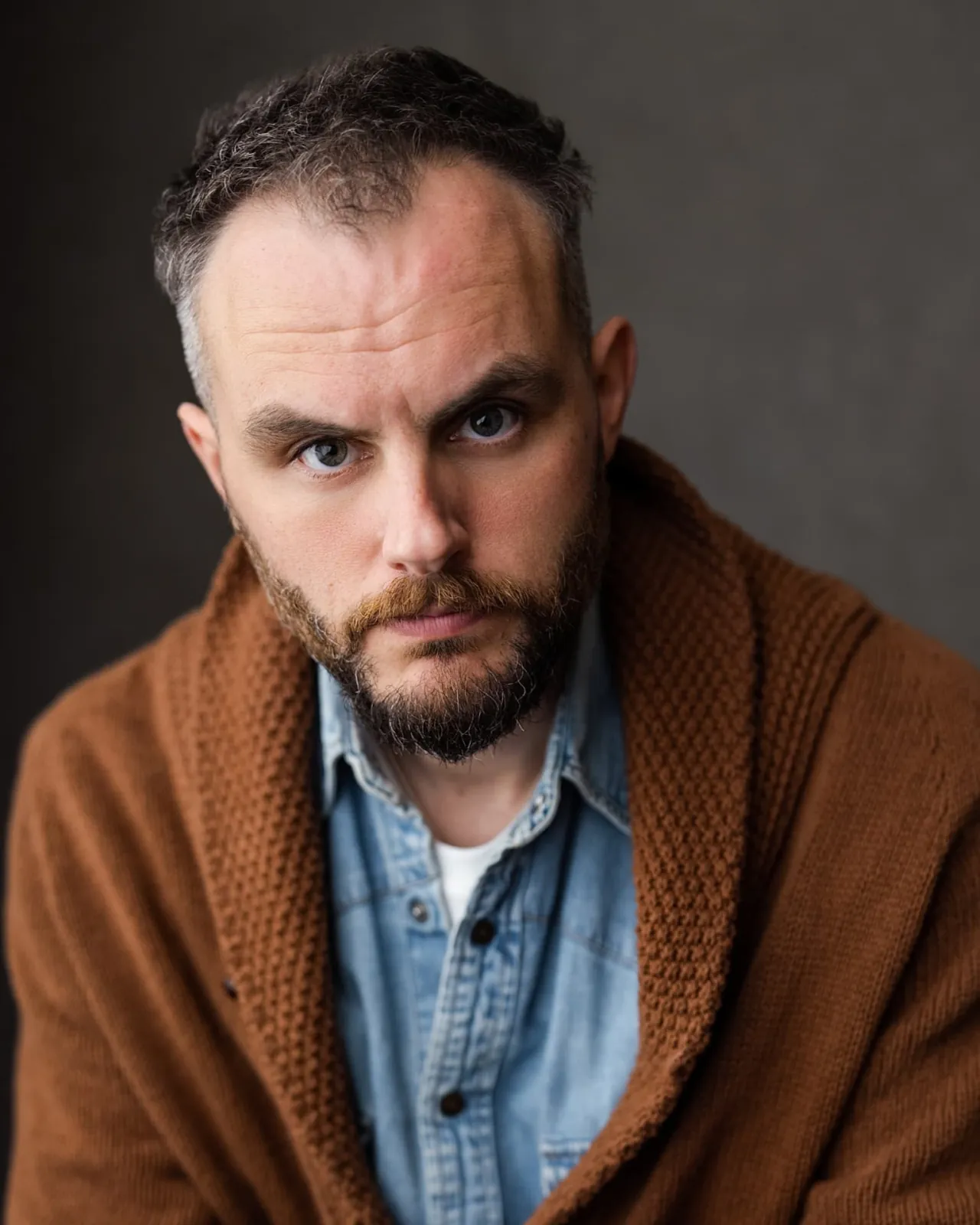 Danny Solomon headshot — brown cardigan over denim