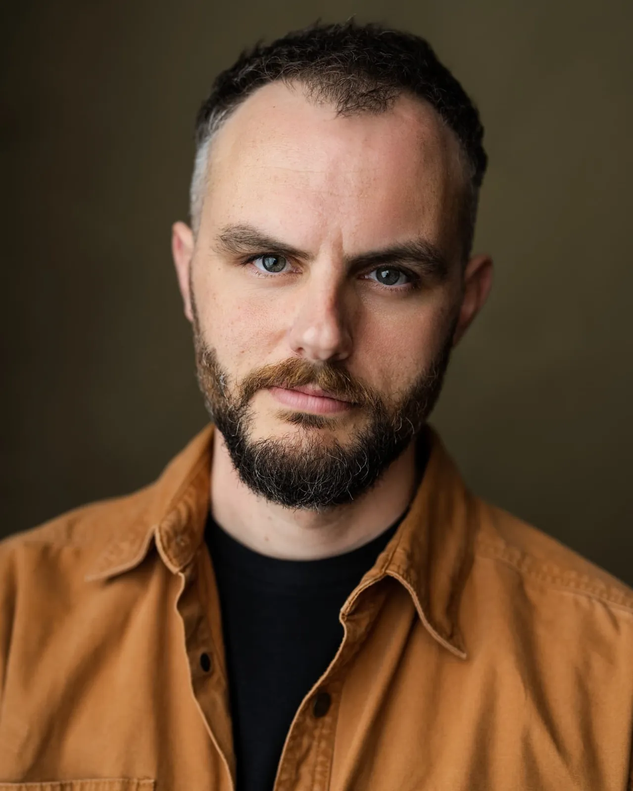 Danny Solomon headshot — tan shirt, olive backdrop